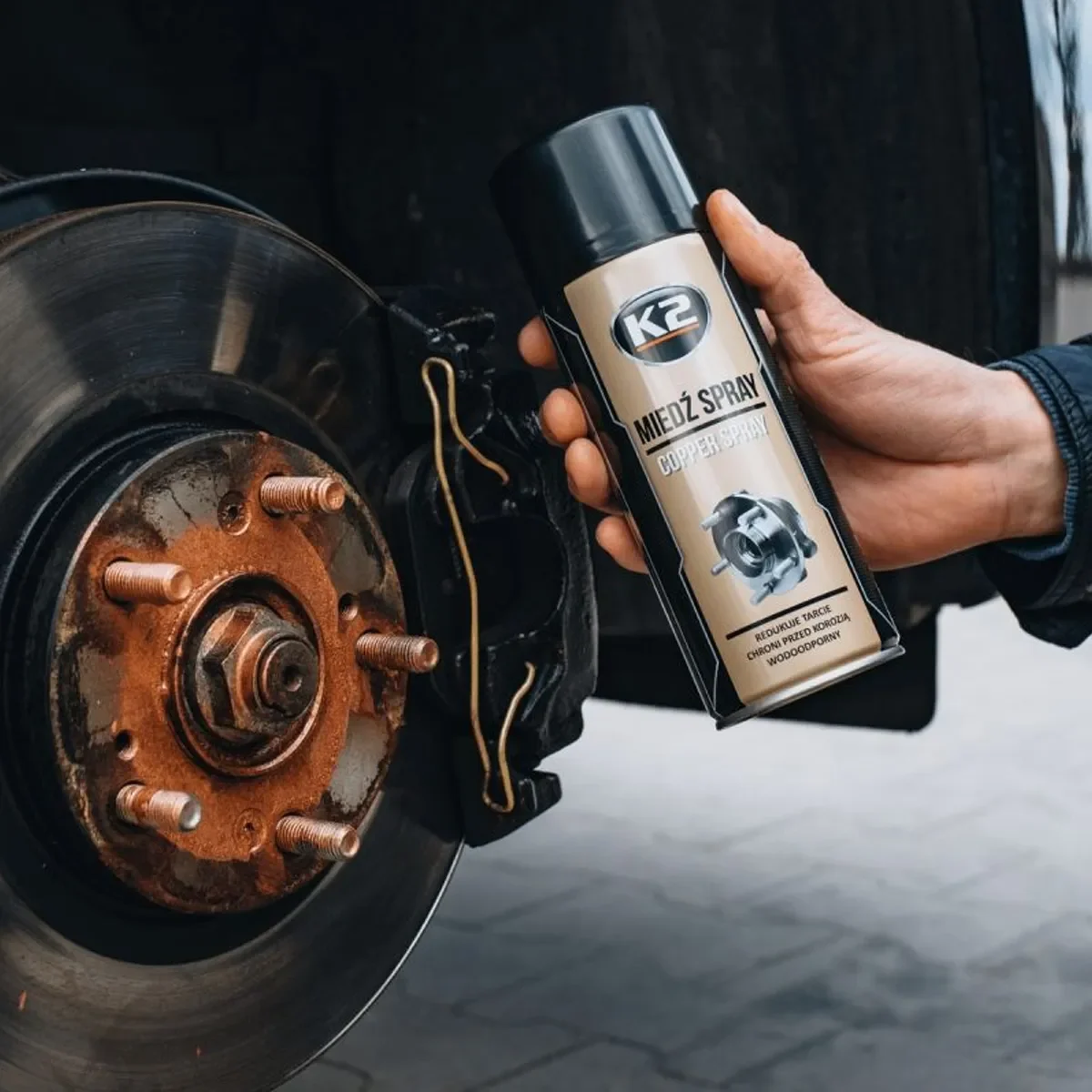 K2 Copper Spray úðabrúsi haldinn við hjólnaf og bremsubúnað.