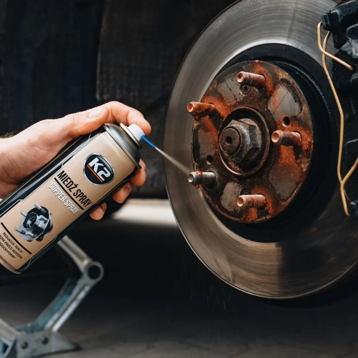 K2 Copper Spray úðað að hjólnafi með bremsudisk í bakgrunni.