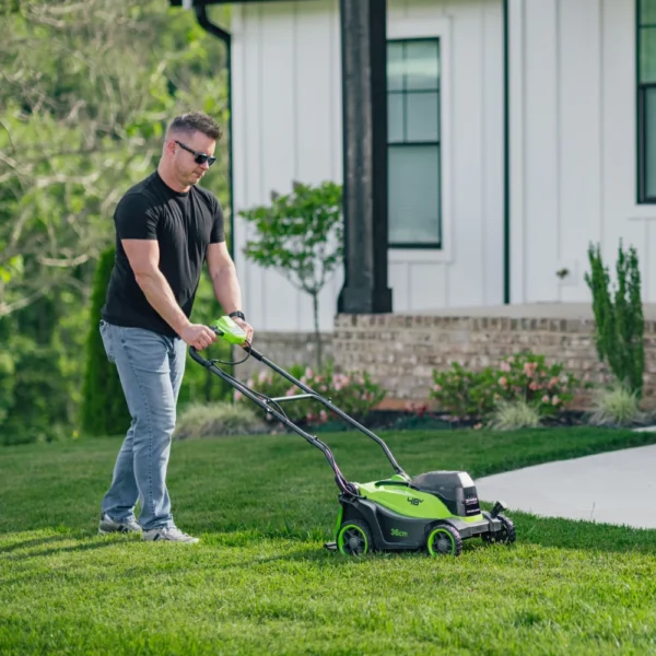 Greenworks 36 cm sláttuvél í notkun á grasflöt, séð frá hlið.