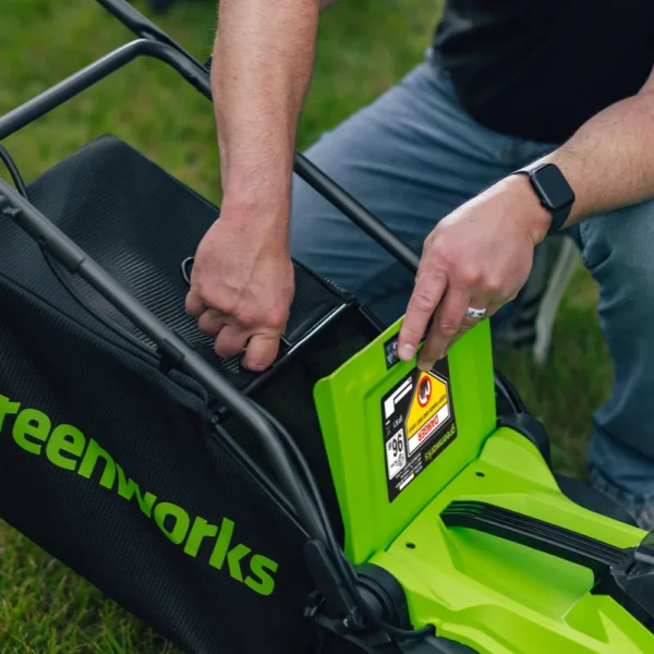 Grassafnari Greenworks 36 cm sláttuvélar losaður undan upplyftri afturhlíf.